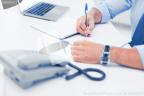 Image of businessman writing in notebook