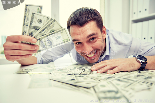 Image of happy businessman with heap of money in office