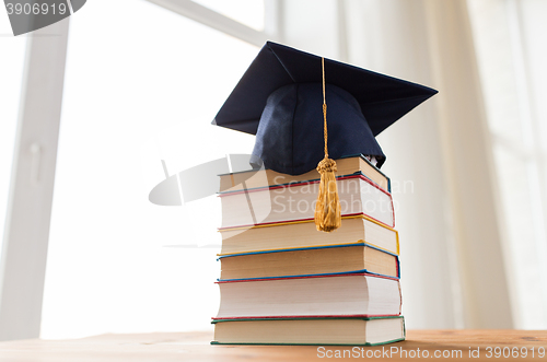 Image of close up of books and mortarboard on wooden table