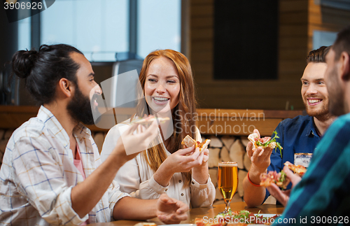 Image of friends eating pizza with beer at restaurant