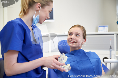 Image of happy dentist showing jaw model to patient girl