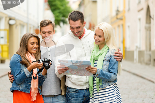 Image of group of smiling friends with map and photocamera