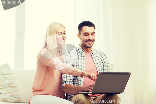 Image of smiling happy couple with laptop computer at home