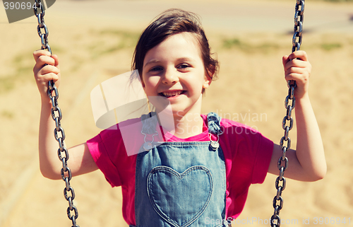 Image of happy little girl swinging on swing at playground