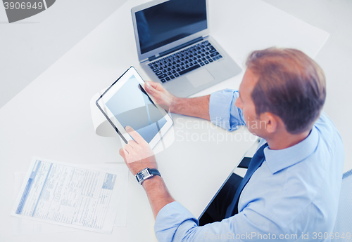 Image of businessman with tablet pc and papers in office