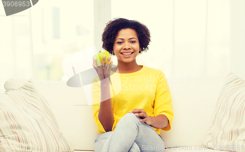 Image of happy african american woman with green apple