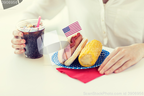 Image of close up of woman eating hot dog with cola