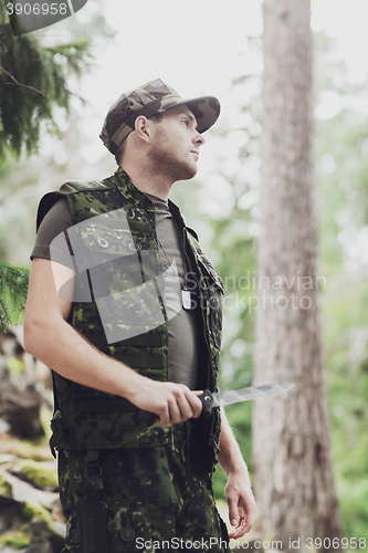 Image of young soldier or hunter with knife in forest