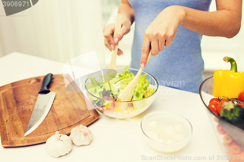 Image of close up of woman cooking vegetable salad at home