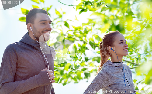 Image of happy couple with earphones running in city
