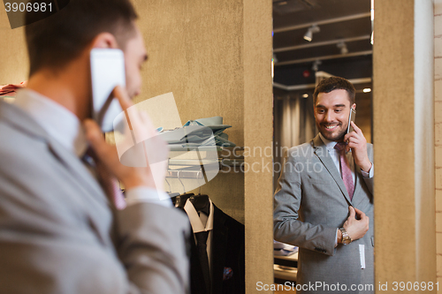 Image of man calling on smartphone at clothing store mirror