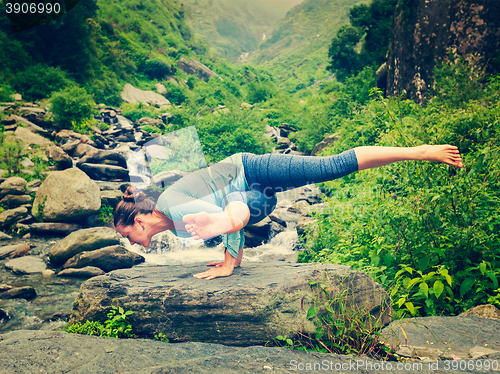 Image of Young sporty fit woman doing yoga oudoors at tropical waterfall