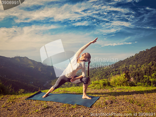 Image of Woman practices yoga asana Utthita Parsvakonasana outdoors