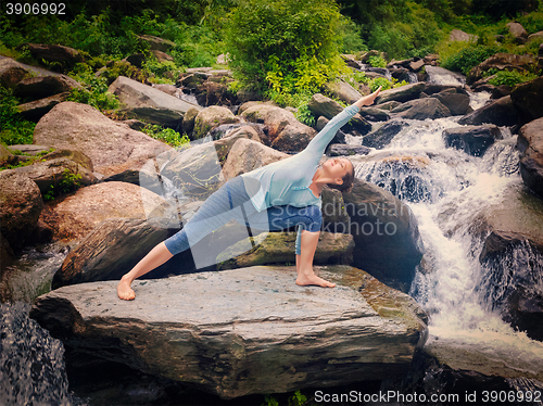 Image of Woman practices yoga asana Utthita Parsvakonasana outdoors