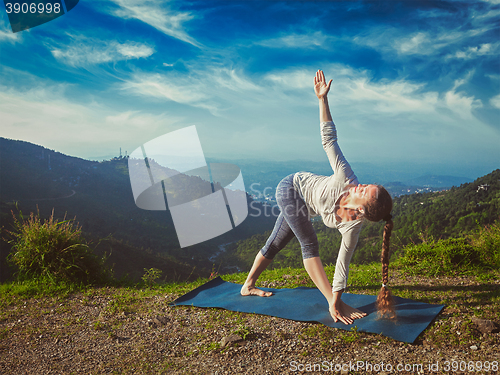 Image of Woman doing Ashtanga Vinyasa yoga asana Parivrtta trikonasana