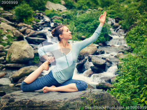 Image of Sorty fit woman doing yoga asana outdoors at tropical waterfall