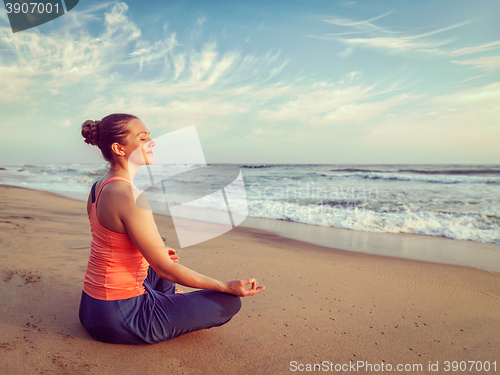 Image of Young sporty fit woman doing yoga oudoors at beach