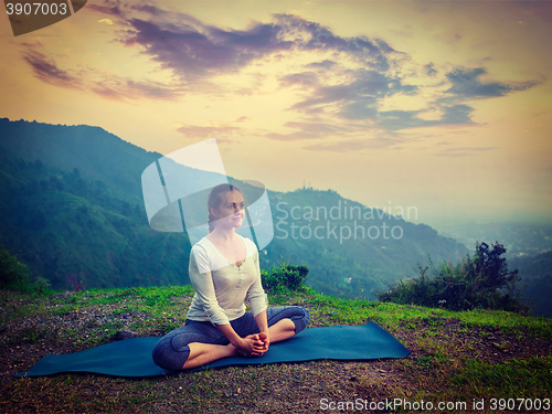 Image of Sporty fit woman practices yoga asana Baddha Konasana outdoors