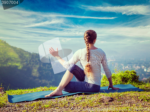 Image of Woman practices yoga asana Marichyasana 