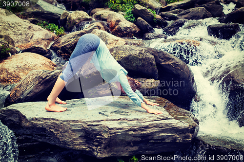 Image of Young sporty fit woman doing yoga oudoors at tropical waterfall