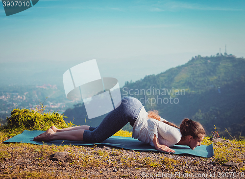 Image of Woman doing yoga asana Ashtangasana outdoors