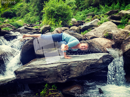 Image of Young sporty fit woman doing yoga oudoors at tropical waterfall