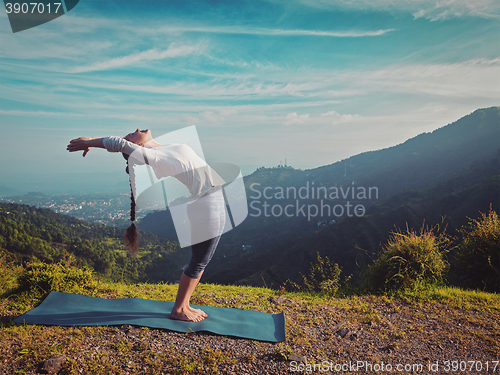 Image of Woman doing yoga Sun salutation Surya Namaskar outdoors