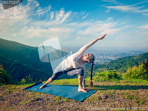 Image of Woman practices yoga asana Utthita Parsvakonasana outdoors