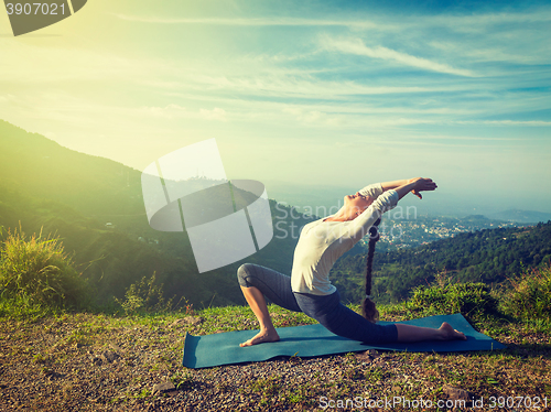 Image of Sporty fit woman practices yoga Anjaneyasana in mountains