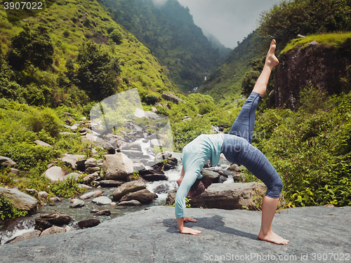 Image of Woman doing yoga asana at waterfall