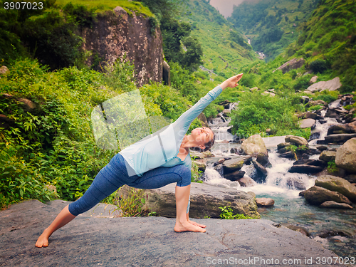 Image of Woman practices yoga asana Utthita Parsvakonasana outdoors