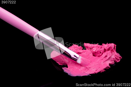 Image of lipstick with a brush make-up on black 