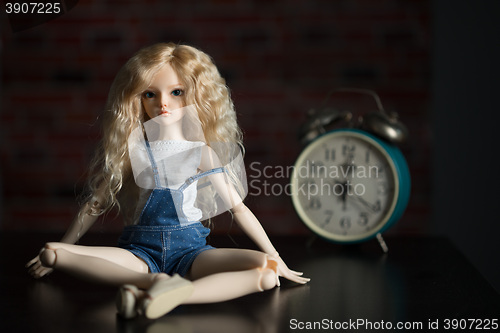 Image of doll on the background of the old clock.