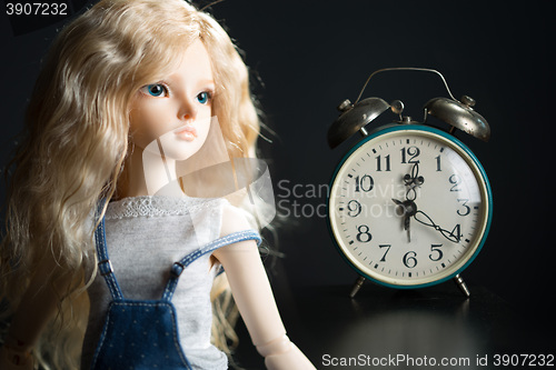 Image of doll on the background of the old clock.