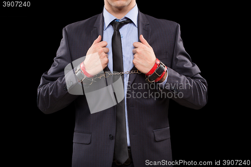 Image of man in a business suit with leather bound. handcuffs. sex Toys
