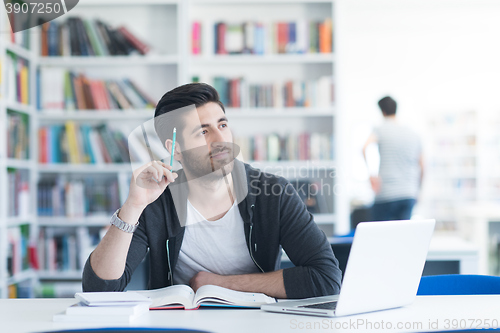 Image of student in school library using laptop for research