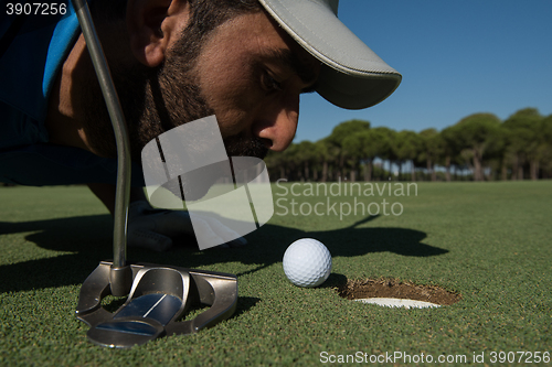 Image of golf player blowing ball in hole