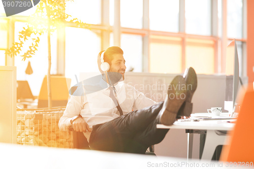 Image of relaxed young businessman first at workplace at early morning