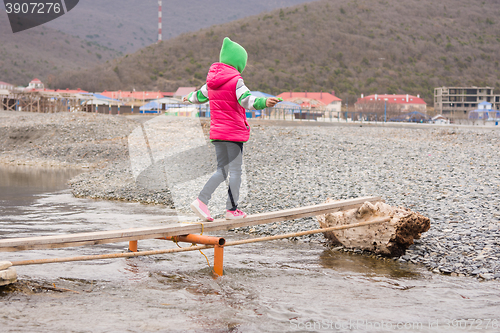 Image of The little girl nearly went to the other side of the stream on the board