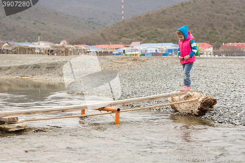 Image of Five-year girl timidly comes on board thrown across the stream