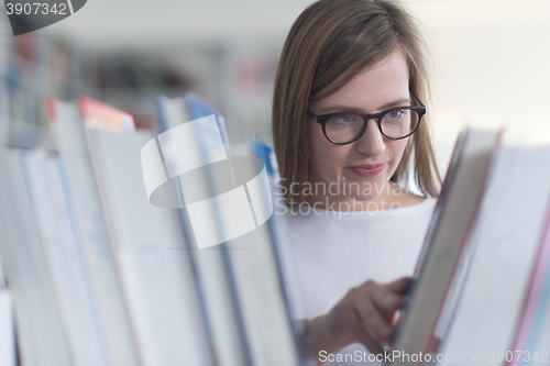 Image of portrait of famale student selecting book to read in library