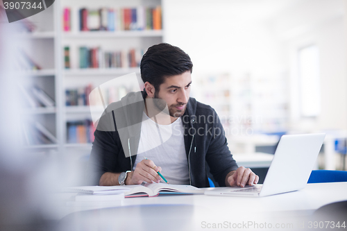 Image of student in school library using laptop for research