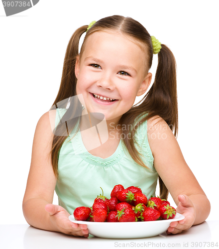 Image of Cheerful little girl is eating strawberries
