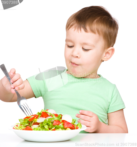 Image of Cute little boy is eating vegetable salad