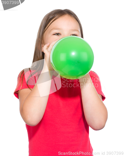 Image of Little girl is inflating green balloon