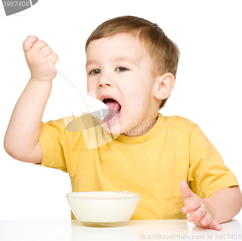 Image of Cute little boy is eating cottage cheese