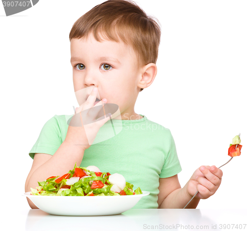 Image of Cute little boy is eating vegetable salad