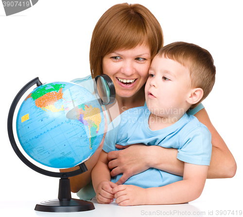 Image of Mother is looking at globe with her son