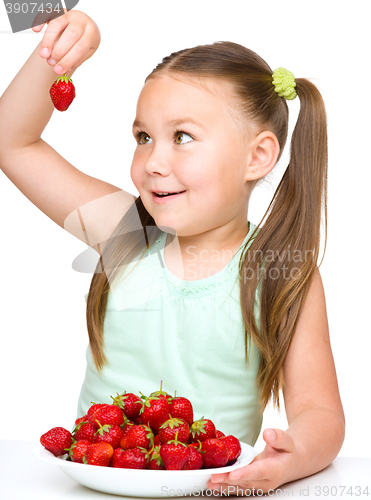 Image of Cheerful little girl is eating strawberries