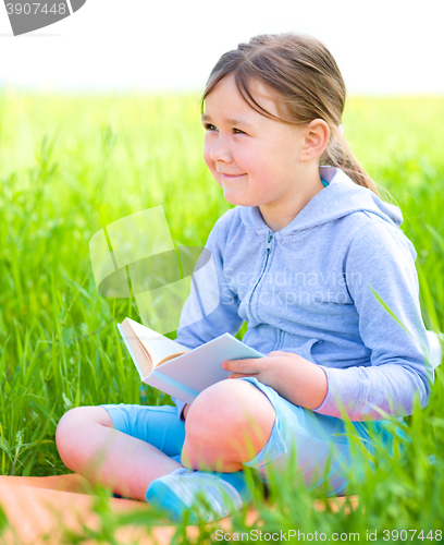 Image of Little girl is reading a book outdoors